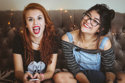 Zwei lachende junge Frauen auf einer Couch