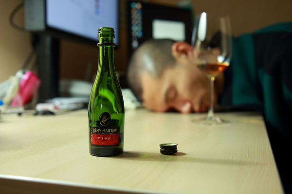 Leere Flaschen und ein erschöpfter Mann am Schreibtisch