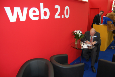 Mann sitzt an einem Messestand und schreibt